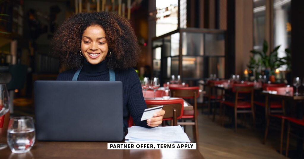 Rippling Company Card overview: Is it price it? social image partner offers terms apply restaurant owner using laptop and holding credit card southw.jpeg