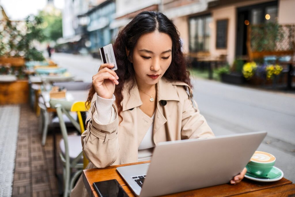 woman in cafe using credit card while on laptop nastasic.jpg