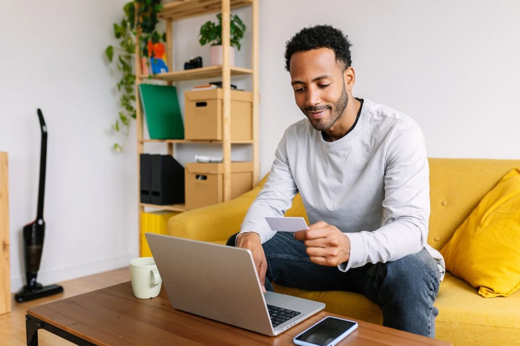 Wyndham Rewards promotion: Earn as much as 30,000 bonus issues person holding credit card at home while using laptop in living room xavier lorenzo.jpg